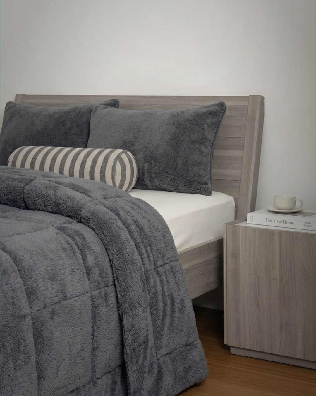 Gray bedding set on a bed with a wooden headboard and nightstand.