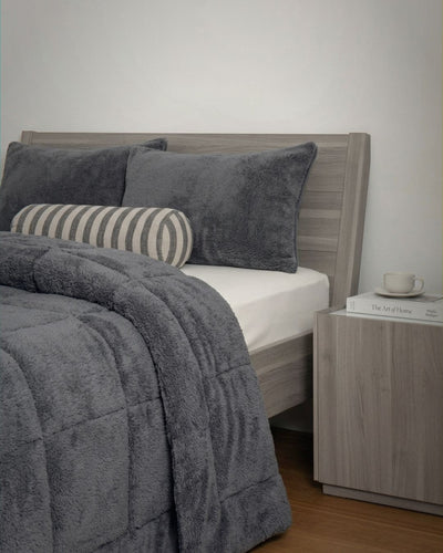 Gray bedding set on a bed with a wooden headboard and nightstand.