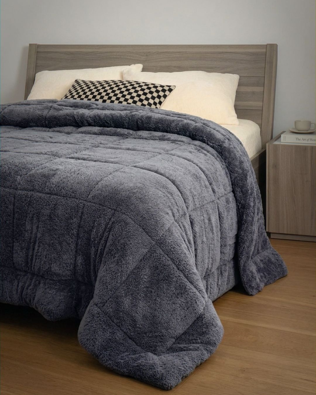 Gray comforter on a bed with pillows and a wooden headboard.