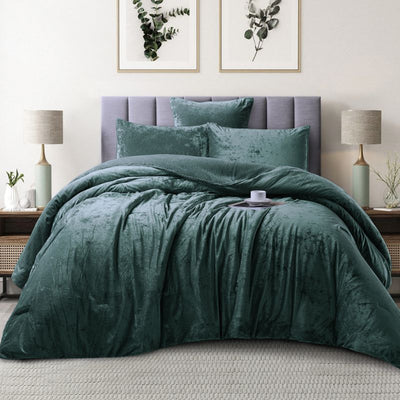 Green textured comforter set on a bed in a bedroom with lamps and wall art.