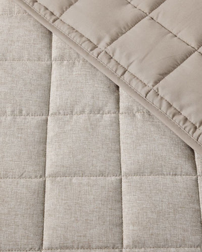 Close-up of a quilted fabric with a diamond pattern in beige color.
