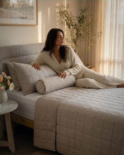 Woman lounging on a bed in a cozy bedroom with soft lighting