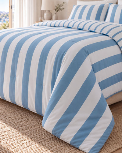 Blue and white striped bedding set on a bed, featuring a comforter and matching pillowcases in a bright bedroom setting.
