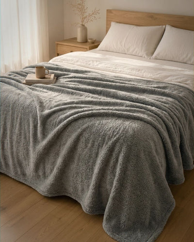 Gray blanket draped over a bed in a bedroom setting