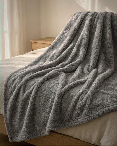 Gray blanket draped over a bed in a softly lit room