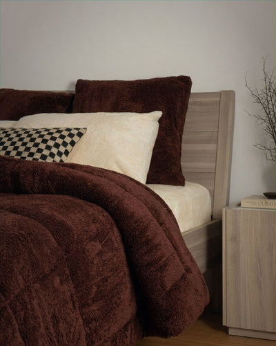 Bed with brown comforter and pillows in a bedroom setting.