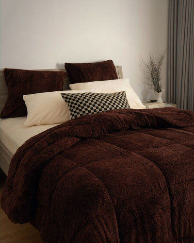 Bed with brown comforter and pillows in a bedroom setting
