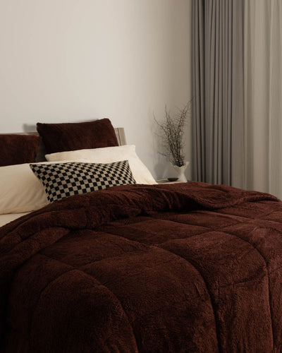 Brown comforter on a bed with pillows in a bedroom setting