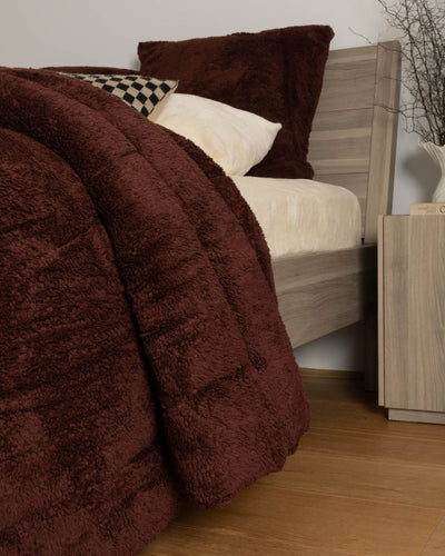 Brown textured comforter on a bed with wooden headboard and nightstand.