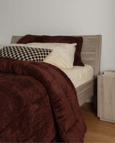 Bed with brown comforter and pillows in a bedroom setting