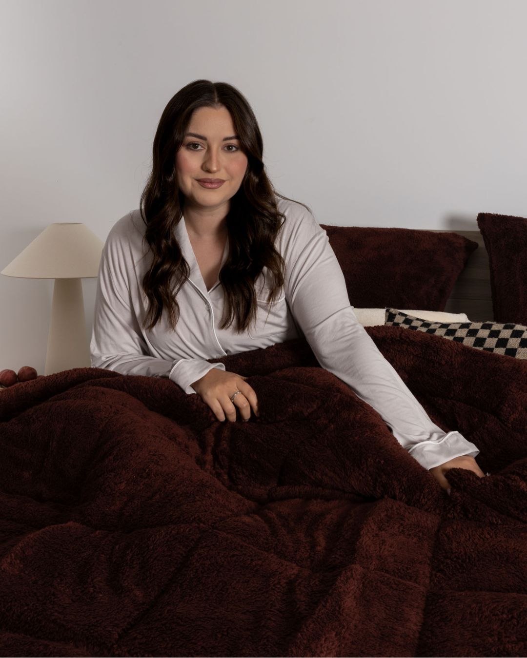 Woman sitting on a couch under a brown blanket in a cozy living room.