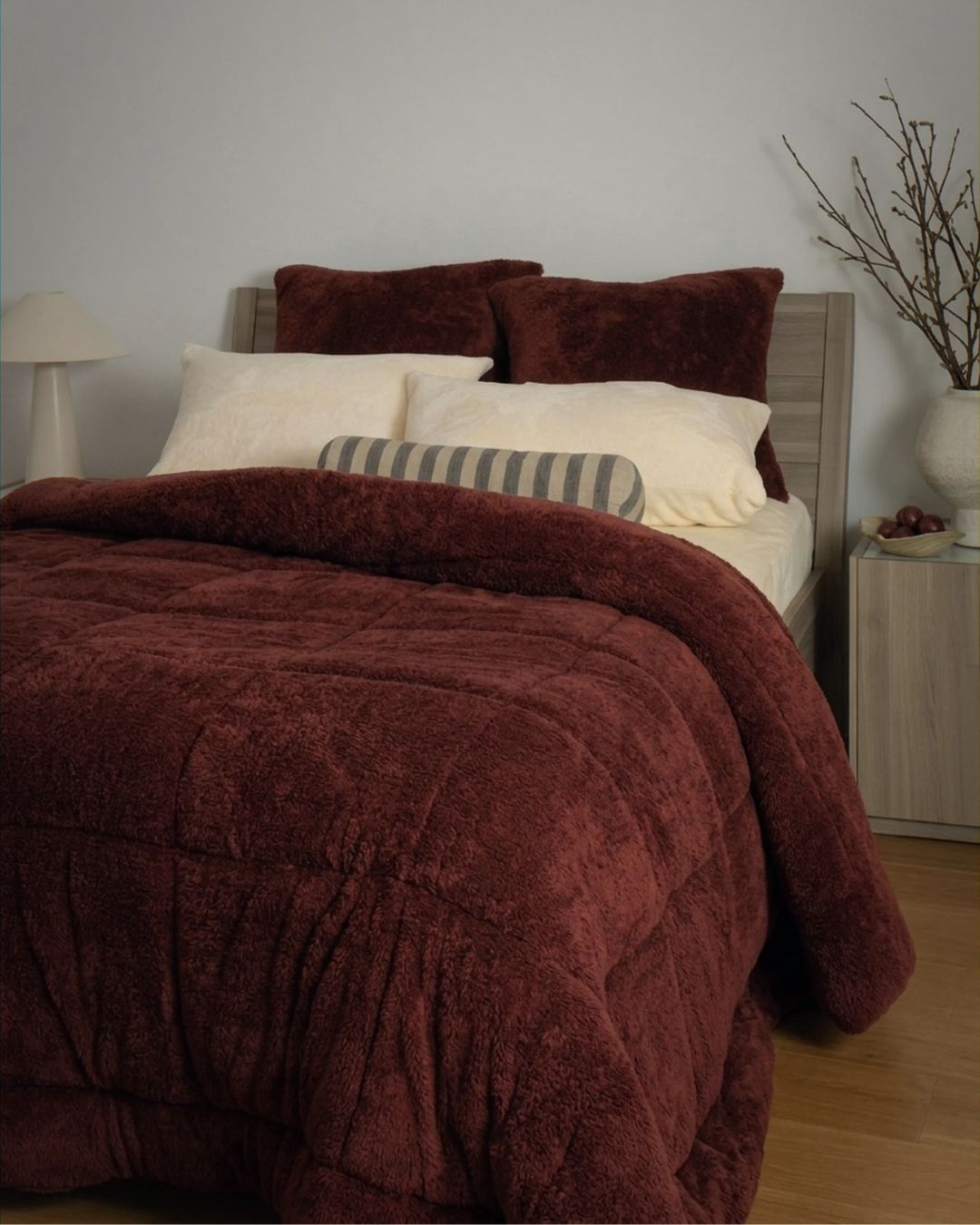 Bed with burgundy chocolate comforter and pillows in a bedroom setting