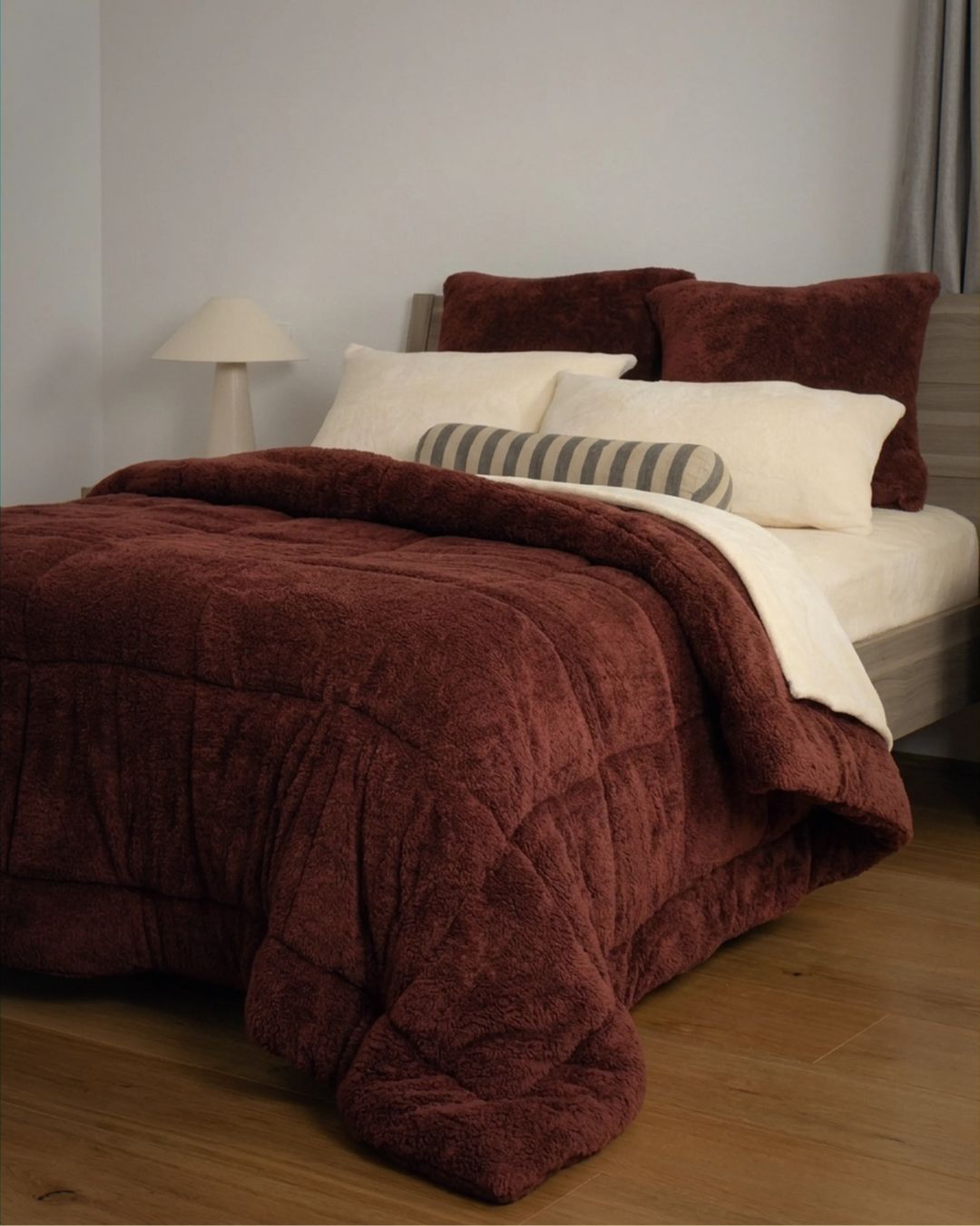 Brown textured comforter on a bed with pillows in a bedroom setting.