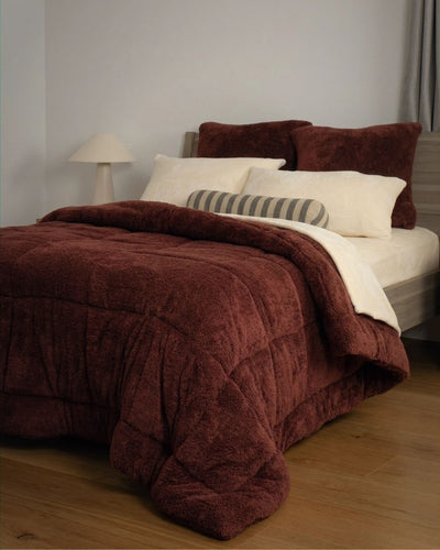 Brown textured comforter on a bed with pillows in a bedroom setting.