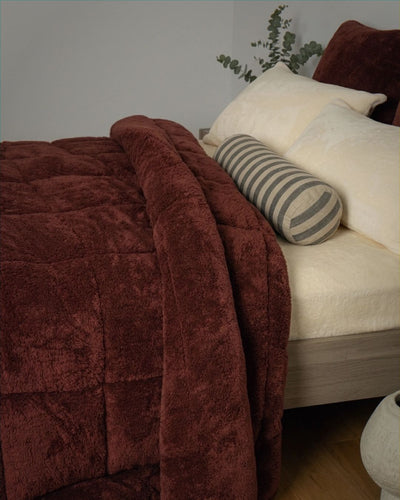 Brown textured blanket draped over a white sofa with decorative pillows.