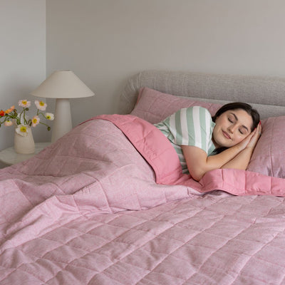 Woman sleeping in a bed with pink bedding and striped pillow