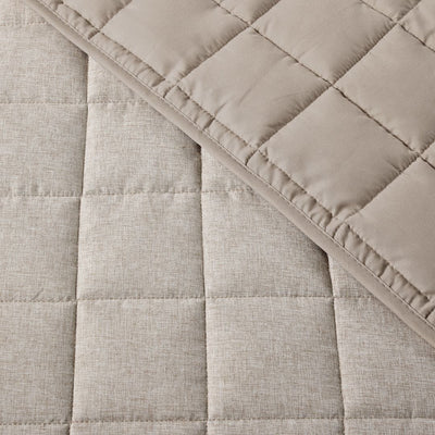 Close-up of a quilted fabric with diamond pattern in beige color.
