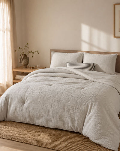 Neatly made bed with light-colored bedding in a softly lit bedroom.