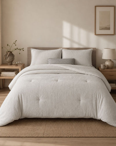 Neatly made bed with light-colored bedding in a bedroom setting.
