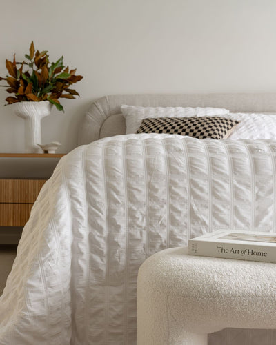 Neatly made bed with white bedding in a bedroom setting.