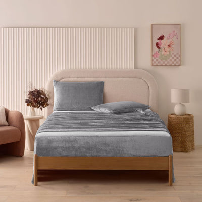 A modern bedroom with a beige upholstered bed and cream bedding exudes winter comfort, enhanced by the Morgan and Reid Winter Microplush Sheet Sets ultra-soft fabric, neutral decor, dried flowers, and light wood floors.