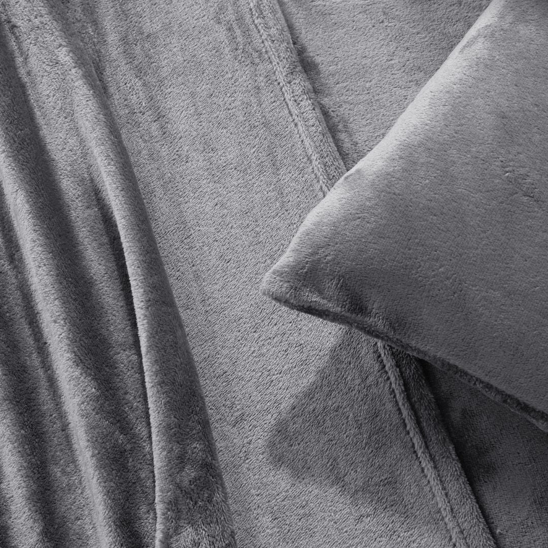 A modern bedroom with a beige upholstered bed and cream bedding exudes winter comfort, enhanced by the Morgan and Reid Winter Microplush Sheet Sets ultra-soft fabric, neutral decor, dried flowers, and light wood floors.