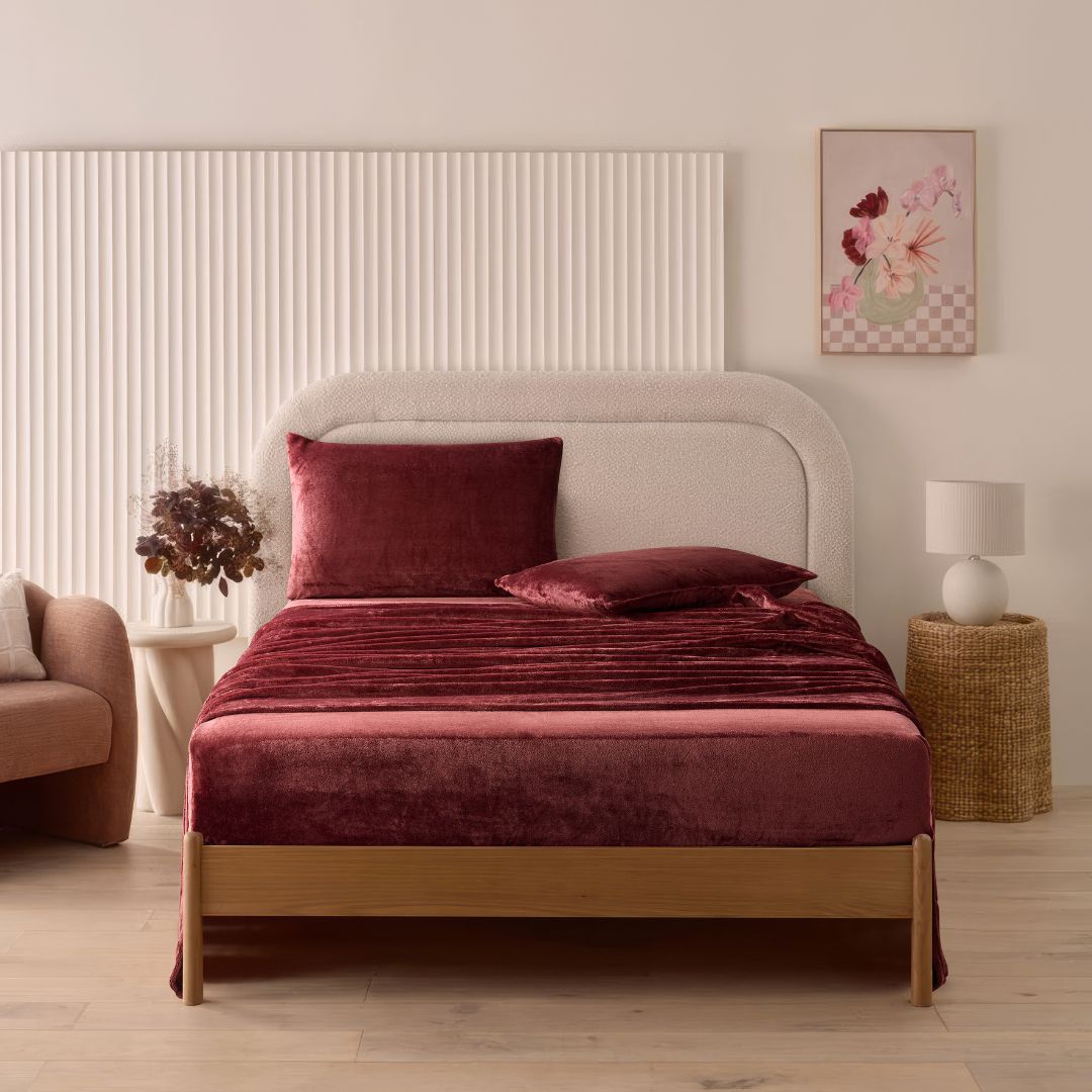 A modern bedroom with a beige upholstered bed and cream bedding exudes winter comfort, enhanced by the Morgan and Reid Winter Microplush Sheet Sets ultra-soft fabric, neutral decor, dried flowers, and light wood floors.