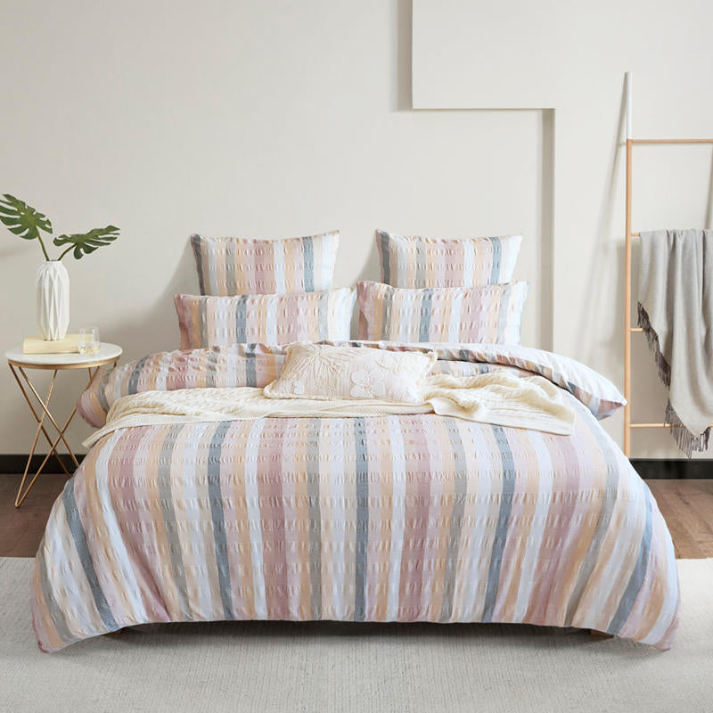 Styled bed featuring Renee Taylor Layla European Pillowcases in blush, peach, and grey tones.