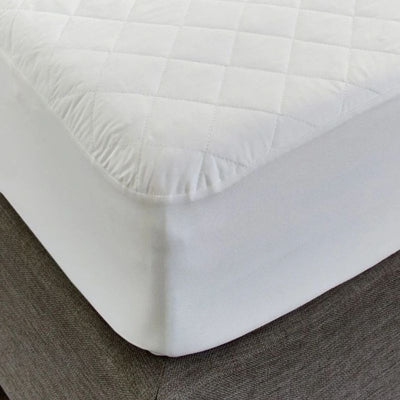 Close-up of the Sienna Living Premium Cotton Mattress Protector featuring a quilted cotton japara cover and diamond stitch pattern, fitted securely over a mattress with a grey upholstered base. Knit stretch skirt ensures a snug fit around corners.