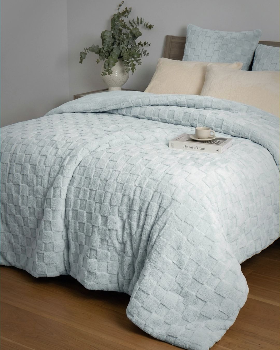 Soft blue checkered snuggle fleece comforter set styled on bed with matching pillows and eucalyptus decor